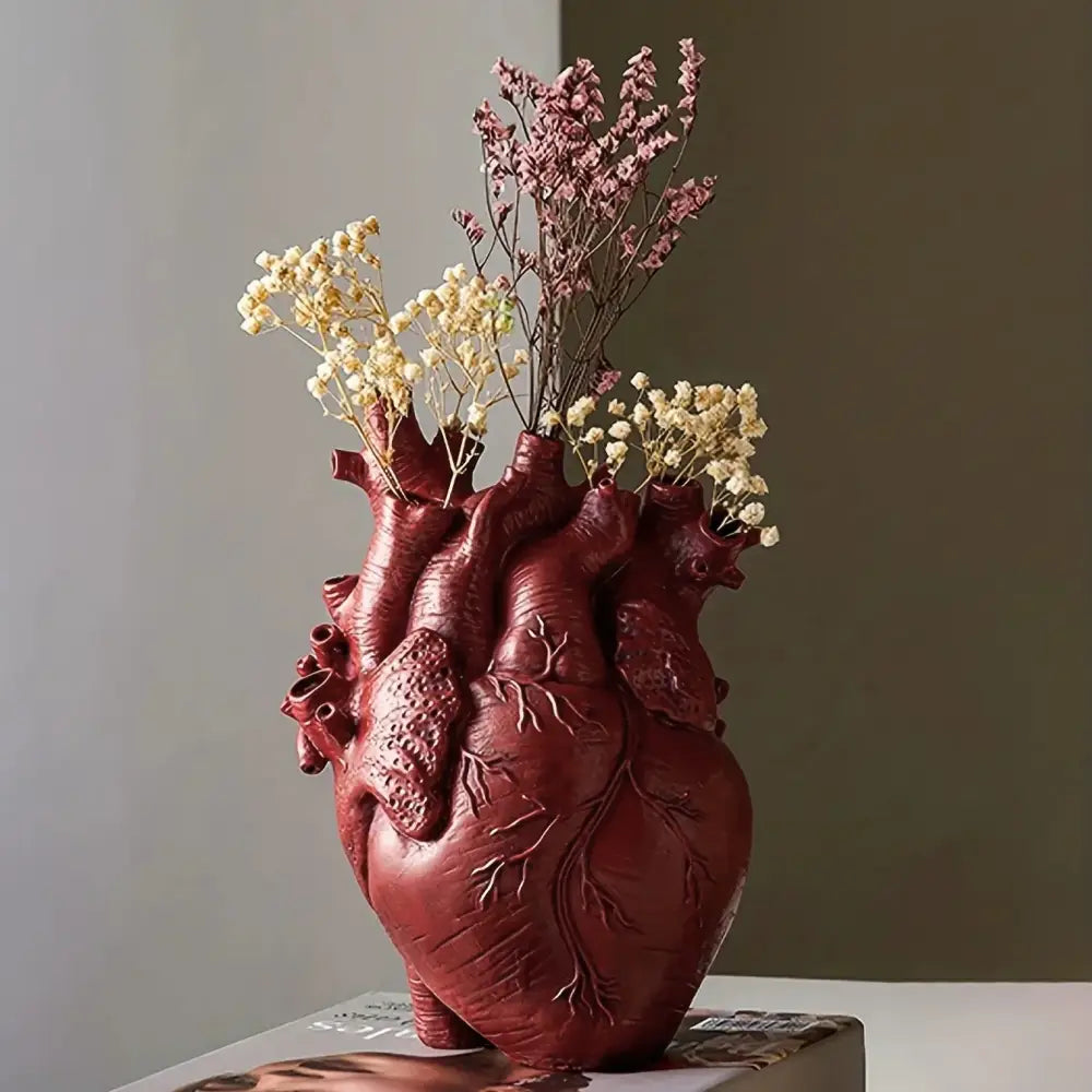 Deep red resin anatomical heart vase with intricate vein textures holding dried flowers for glam decor by decorbites