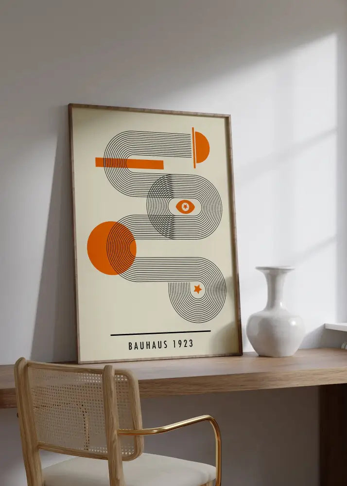 A framed decorbites™ bauhaus geometric art canvas print in orange and black with cream background in a light wood frame