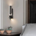 Modern brushed stainless steel bedroom wall reading lamp with sleek cylindrical body and adjustable spotlight head