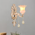 Chic gold and pink crystal wall lamp featuring an ornate gold-toned sconce with a translucent pink glass shade and crystal pendants