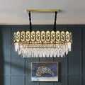 Gold island crystal shaded hanging lamp with gold-toned frame, black cords, and clear crystal prisms on decorative panel