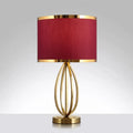 Elegant gold-toned metal round table lamp with deep red fabric shade accented by golden rims for study room use