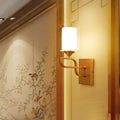 Contemporary gold armed sconce light with cylindrical frosted glass shade and elegant curved metal arm for bedroom use