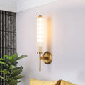 Contemporary gold brass cylinder wall light fixture with cylindrical ridged glass shade and warm diffused lighting