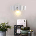 Contemporary white ceramic wall lamp with sculpted petal design and clear glass round wall element for bedroom use