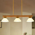 Contemporary wood linear island ceiling light featuring warm tones, frosted glass shades, and gold black brass accents