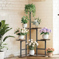 Black metal corner plant stand with wooden shelves holding white ceramic pots and floral arrangements by DecorBites™