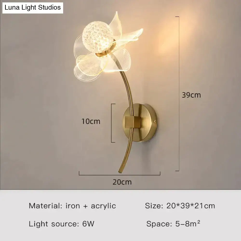 A creative floral decorative gold led wall lamp with translucent acrylic petals and a crystal center for bedroom use