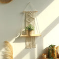 Beige macrame hanging shelf with wooden wall shelf holding potted plant for boho home decor by decorbites