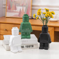 Green glittery ceramic robot vase holding yellow flowers in nordic style home decor by decorbites