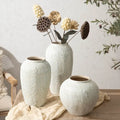 Three textured white ceramic vases in chinese style with one holding dried flowers for home decor by DecorBites™