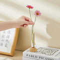 DecorBites clear vase with bamboo base holding two pink daisies as a hydroponic vase tabletop decoration