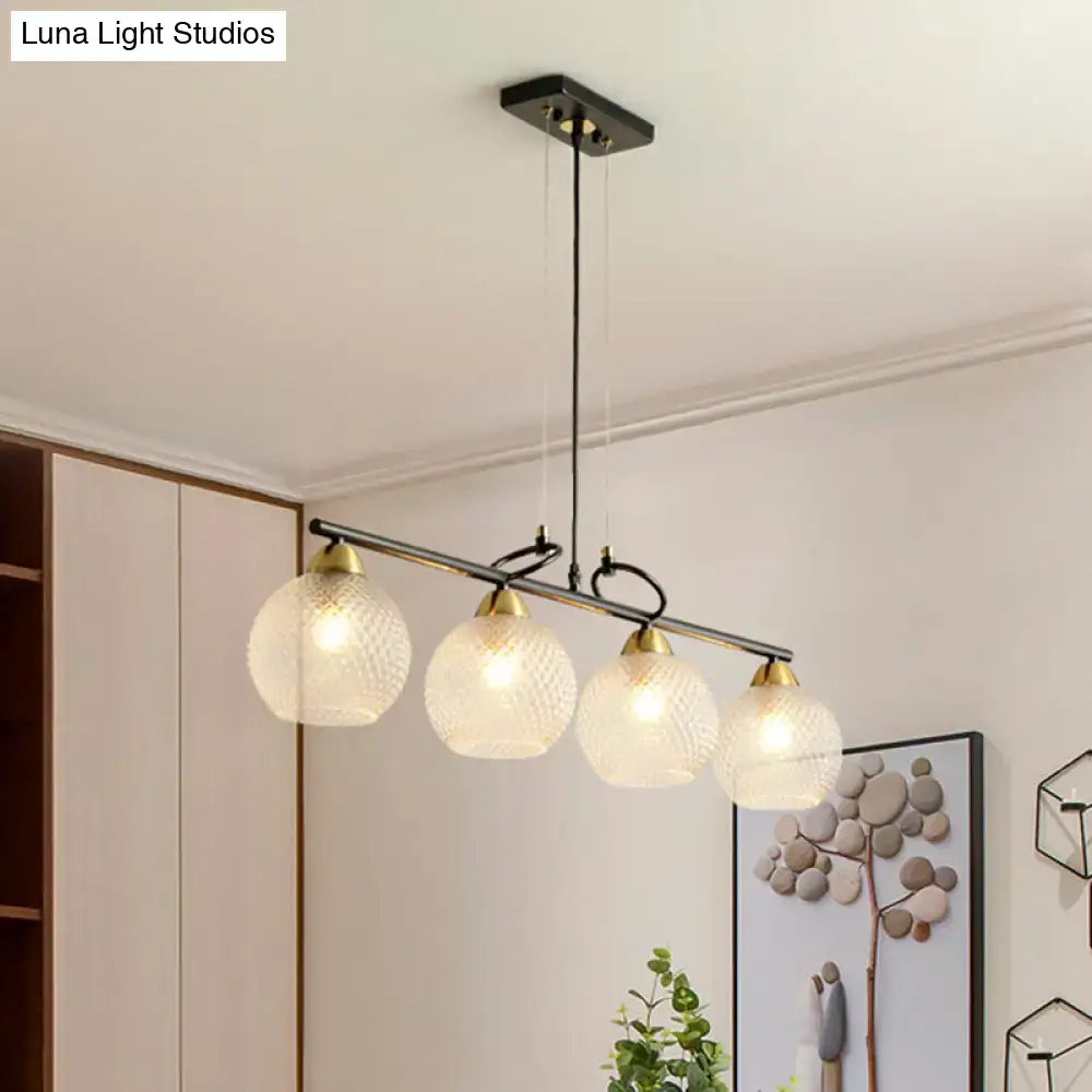 Modern black metal pendant light with four frosted globe shades and brass accents featuring clear prismatic glass for dining hall