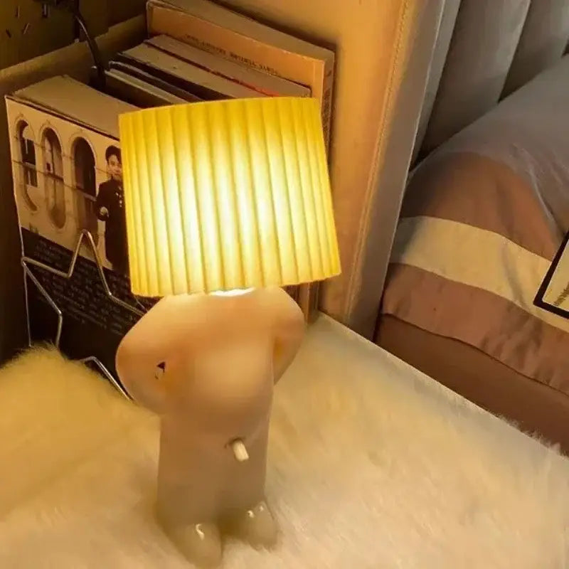 Beige whimsical figurine creative table lamp with pleated yellow shade ideal for bedside reading and children’s rooms