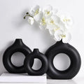Set of three black ceramic donut shape flower vases with circular cutouts and a matte minimalist design by DecorBites™