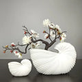 Decorbites™ elegant ceramic vase with shell conch design in white holding artificial white blossoms with ribbed texture