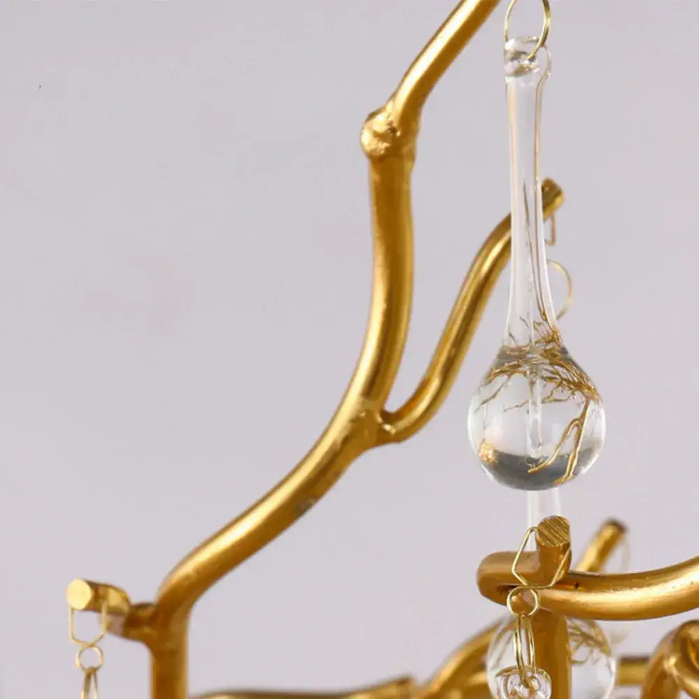 A clear glass teardrop pendant with gold wire detailing hangs from a golden metal frame in a decorbites crystal chandelier for living room lamp package