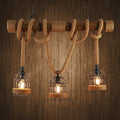 Rustic industrial ceiling light with three cast iron birdcage bulbs hanging by hemp rope from a wooden beam