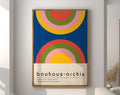 A geometric bauhaus canvas poster featuring bold concentric rainbow arcs in red yellow green and pink on deep blue