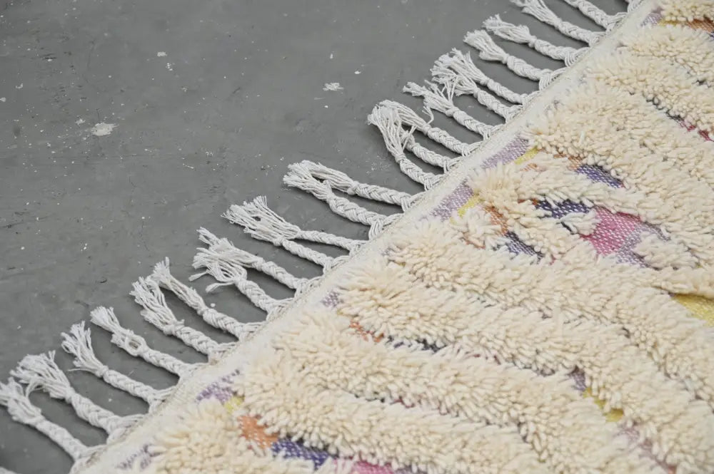 Cream-colored plush wool handmade moroccan azilal rug with fringed edge and multicolored geometric patterns 223x133 cm