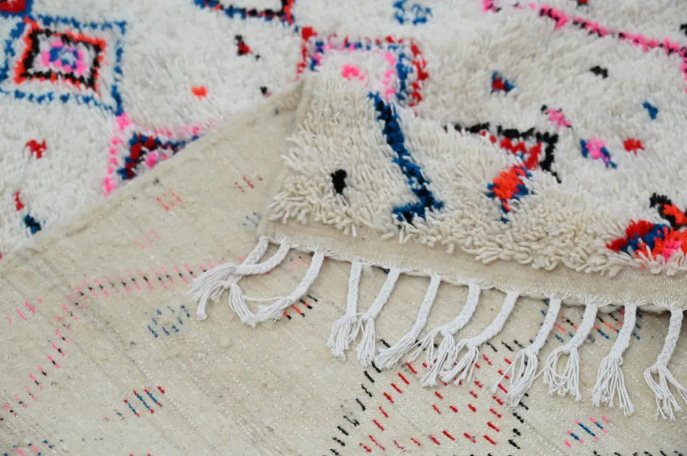 Cream-colored decorbites™ handmade traditional azilal rug with white fringe and vibrant geometric patterns 230x154cm