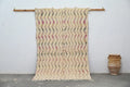 Beige woven handmade moroccan azilal rug with zigzag pattern in muted pink and olive green with fringed edges