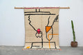 Beige woven decorbites™ handmade moroccan azilal rug with bold black orange pink geometric patterns and fringed edges