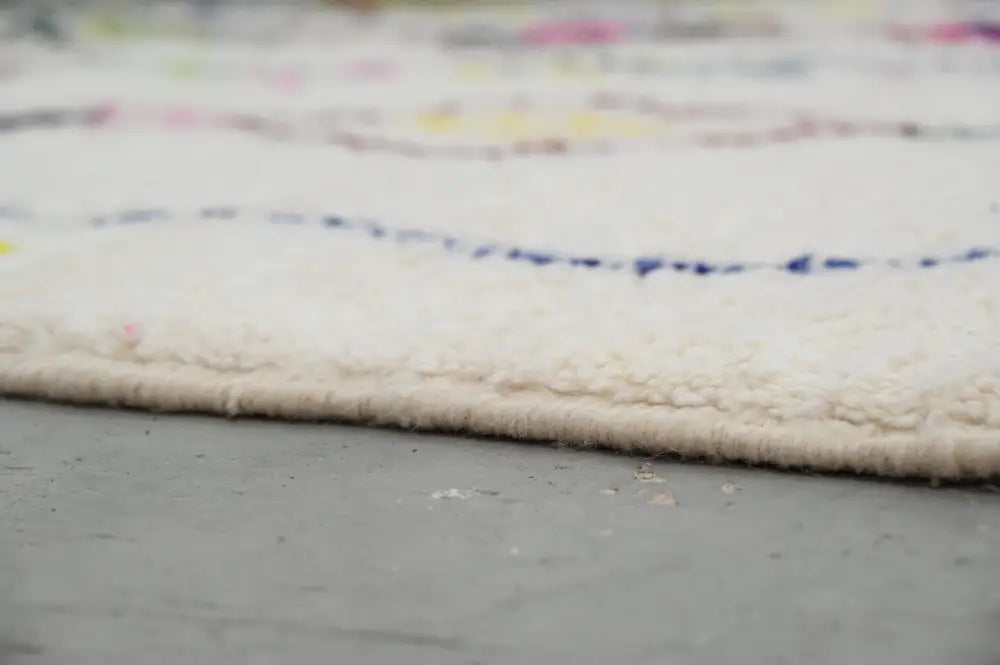 Cream-colored DecorBites™ handmade moroccan azilal rug with soft pile and colorful wavy patterned border 293x206cm