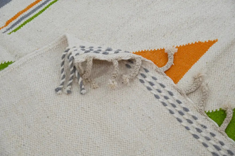 A cream-colored moroccan handmade azilal rug with orange green and gray geometric stripes and triangles 300x192 cm