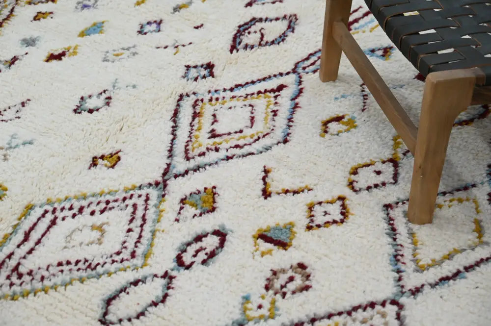 Cream-colored handmade Moroccan Azilal rug with maroon yellow and muted blue geometric patterns 305x206cm by DecorBites