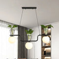 Modern black metal pendant light with three opal glass globes and clear glass pots holding green plants by DecorBites™