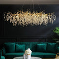 Golden leaf-shaped luxury crystal chandelier with clear crystal droplets and LED lights above green velvet sofa living room