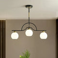 Modern arched island pendant light with clear white glass globe shades and black brass finish in a three-light design