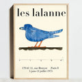 A framed poster featuring a stylized blue bird with orange legs on an off-white background from decorbites modern geometric bauhaus exhibition posters