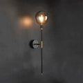 DecorBites™ modern glass wall sconce with spherical amber glass bulb and black metal stem accented by gold hardware