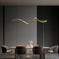 Gold-colored sleekly curved modern led chandeliers pendant lights hanging above a dining table by decorbites