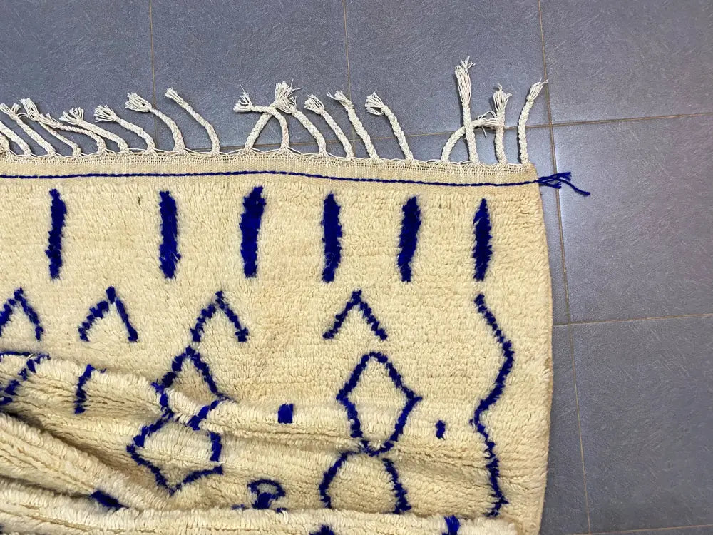 Cream-colored moroccan handmade azilal rug with bold navy blue geometric patterns and white fringe 2.5m x 1.5m