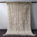 Cream-colored plush moroccan handmade beni ouarain rug with textured geometric pattern and fringed edges 2.5m x 1.5m