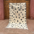 Cream-colored beni ouarain moroccan handmade carpet with black geometric patterns and fringed edges 2.5m x 1.5m