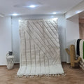 Cream-colored beni ouarain rug with textured geometric pattern and fringed edges handcrafted by skilled artisans