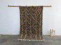 A moroccan handmade azilal rug by decorbites with dark brown base geometric patterns in orange yellow black pure natural wool