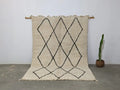 Cream-colored beni ouarain rug with black geometric diamond patterns and fringed edges moroccan handmade traditional design