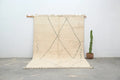 Beige moroccan handmade beni ouarain rug with geometric black lines and fringed edges measuring 303 x 212 cm