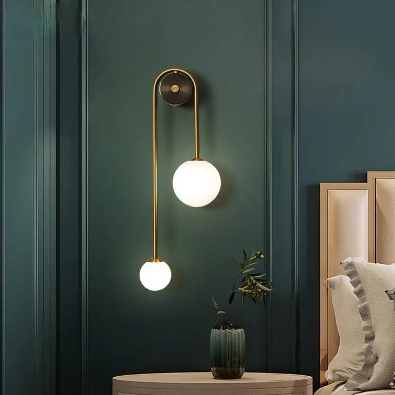Gold wall sconces DecorBites with two spherical frosted glass shades and a curved minimalist design