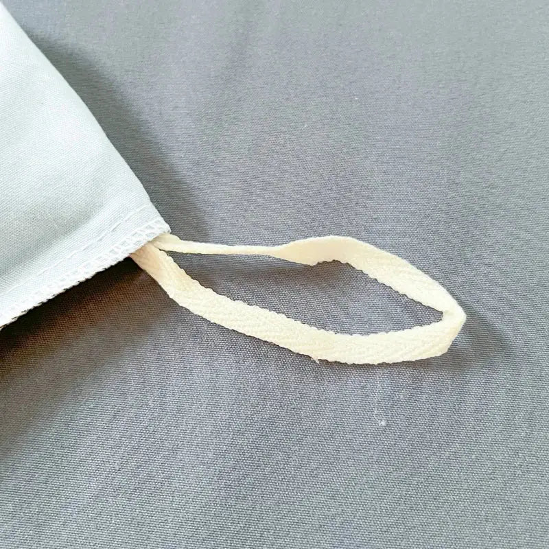 A soft off-white loop detail with textured weave and stitched edges on a solid color brush fabric duvet cover