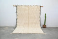 Cream-colored beni ouarain traditional tapis beni with textured handwoven surface and bold black zigzag fringed edges