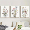Three framed watercolor flower posters with delicate pink white and green blooms on cream canvas for wall decor