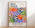 A vibrant bauhaus geometric canvas print in black and orange framed in light wood for modern home decor