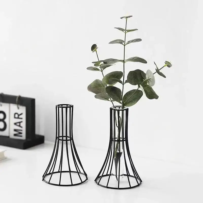 Black metal wireframe vase with flared base holding green eucalyptus branches for modern desk gold vase decoration