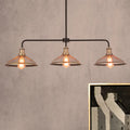 Industrial-style black metal cage flared island pendant light with three brass-finished mesh-shaded lights for dining room